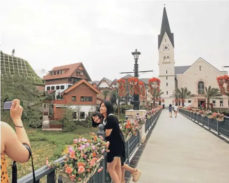  ?? FOTO: AP ?? Turistas chinos toman fotos en Hallstatt See, una réplica de la ciudad austríaca de Hallstatt, edificada en el condado de Boluo, ubicado en la sureña provincia china de Guangdong.