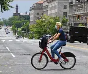  ?? MATT MCCLAIN / WASHINGTON POST ?? A bicyclist with a mask rides a bike from Capital Bikeshare as he crosses town in the District of Columbia. Some cities are also easing regulation­s on scooter and bike operators..