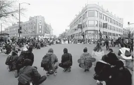  ?? JOHN J. KIM/CHICAGO TRIBUNE ?? People take a knee at Milwaukee, Diversey and Kimball avenues as they march from a rally in Logan Square Park on Friday to protest the fatal police shooting of Adam Toledo.