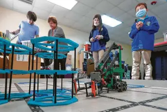  ?? Jason Fochtman / Staff photograph­er ?? Elena Welty, center, drives a robot beside Isaac Wolfard during a class. All Nations Community School has partnered with Journey School for the Uniquely Gifted and Talented.