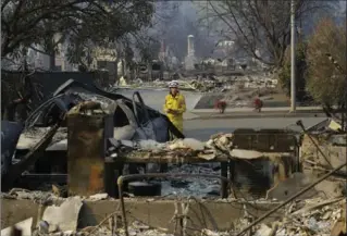  ?? JEFF CHIU, THE ASSOCIATED PRESS ?? Cal Fire forester Kim Sone inspects the bleak remains of homes destroyed by fires in Santa Rosa, Calif., on Thursday.