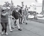  ?? THE ASSOCIATED PRESS ?? President Donald Trump, center, and first lady Melania Trump on Thursday tour a neighborho­od impacted by Hurricane Irma in Naples, Fla.