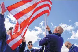  ?? CABLE HOOVER/GALLUP INDEPENDEN­T/VIA AP ?? Hiroshi Miyamura, center, watches as Ken Reige, left, helps Jamie Popwell and Brantley Cargill of Flags for Vets raise a flag on a new flagpole at Miyamura’s home in Gallup. Neighbors can now recognize the house by the new flag pole, which the Flag for...