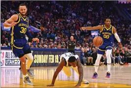  ?? JOSE CARLOS FAJARDO — BAY AREA NEWS GROUP ?? Warriors guard Stephen Curry, left, limps away after colliding with the Mavericks' McKinley Wright IV and injuring his left leg during the third quarter of Saturday night's game.