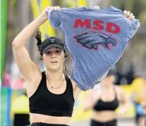  ??  ?? Amy Farber of Parkland, a graduate of Marjory Stoneman Douglas High School, holds a T-shirt from the school at the finish line of the Publix A1A Marathon in Fort Lauderdale on Sunday.