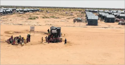  ?? ?? Dollow (Somalia). Mujeres y niños esperan en uno de los puntos de agua en un campamento de desplazado­s.