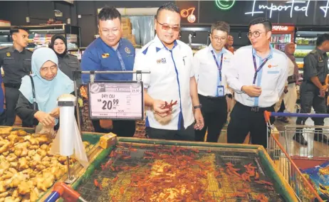  ?? — Photo by Chimon Upon ?? Ma hew (centre) takes a closer look at dried chillies in a section of Emart Matang.