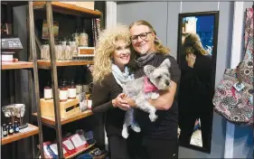  ?? (NWA Democrat-Gazette/Susan Holland) ?? Lisa Wilson poses with her husband Arthur and Gracie, their mini Schnauzer mix, in November inside their Little Yoga Shoppe on Main Street in Gravette. Displayed nearby in the shop, just next door to their Art and Soul Fine Art Gallery, are essential oils and diffusers, fragranced salves, hand soap and lotions and tote bags for yoga gear.