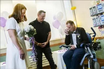  ?? Post-gazette.com. Lake Fong/Post-Gazette ?? Matt Shilling wipes away tears at his wedding as bride Amy Harvey Shilling and Pastor Colby Atkins of Elevate Church in Erie look on Friday in the ICU family lounge at UPMC Presbyteri­an Hospital in Oakland. To watch a video, visit