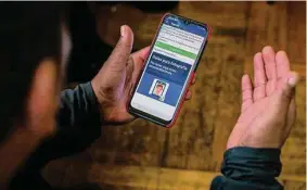  ?? Eduardo Munoz Avarez/Associated Press ?? Ecuadorian immigrant Neptali Chiluisa uses an app in October 2021 to report his location to U.S. immigratio­n authoritie­s in New York.