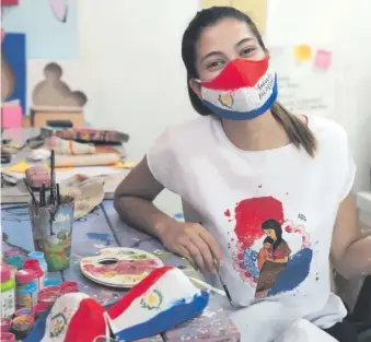  ??  ?? Jessica Bogado comerciali­za tapabocas y otros artículos tricolores pintados a mano, en Itauguá. El número para contactar con ella es el 0983 995830.