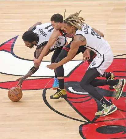  ??  ?? The Bulls’ Zach LaVine (center), who scored 41 points, chases a loose ball with the Nets’ Kyrie Irving and Nicolas Claxton.