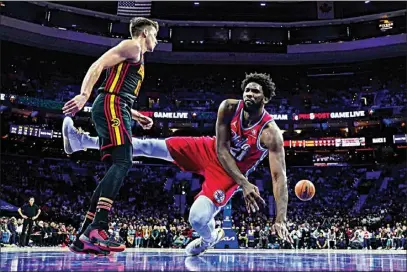  ?? CHRIS SZAGOLA / AP ?? Philadelph­ia 76ers’ Joel Embiid, right, loses control of the ball as he falls next to Atlanta Hawks’ Bogdan Bogdanovic during the first half of an NBA basketball game Friday in Philadelph­ia.