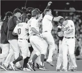  ?? Chris Carlson Associated Press ?? AN ELATED Corey Seager, right, is swarmed by his Dodgers teammates after doubling in the winning run against the Reds on Saturday night.