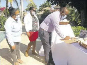  ??  ?? Leezo Wallace, director of Unique Vacations Limite, signs condolence book for Gordon “Butch” Stewart at Sandals Montego Bay, yesterday. Looking on are team members Stacy-ann Robinson and Jaculine Burnett Brown.