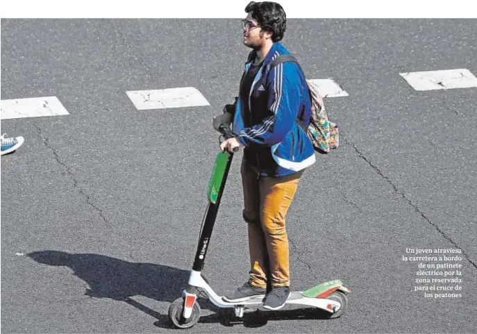  ?? GABRIEL BOUYS / AFP ?? Un joven atraviesa la carretera a bordo de un patinete eléctrico por la zona reservada para el cruce de los peatones