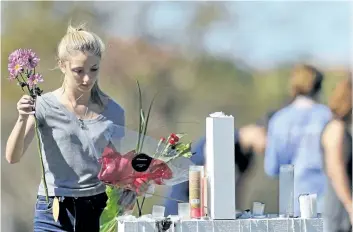  ?? GERALD HERBERT/THE ASSOCIATED PRESS ?? A woman places flowers at one of 17 crosses placed for the victims of Wednesday’s mass shooting at Marjory Stoneman Douglas High School, in Parkland, Fla., on Friday.