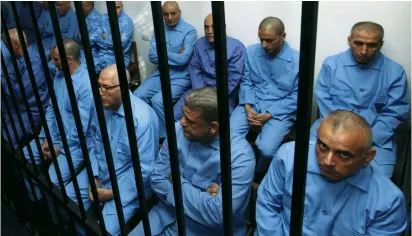  ?? (Ismail Zitouny/Reuters) ?? FORMER GADDAFI regime officials sit behind bars during a verdict hearing at a courtroom in Tripoli yesterday.