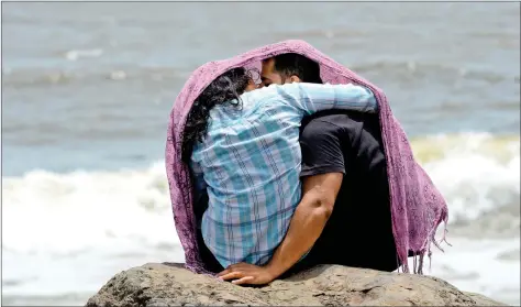  ??  ?? A young couple embraces while sitting on a rocky outcrop off the Arabian Sea in Mumbai on Friday. AFP