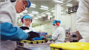  ?? WOOHAE CHO/THE NEW YORK TIMES ?? Factory workers check Spam tins before they are packed at CJ Food Factory in Jecheon, North Chungcheon­g province, South Korea, January 13, 2014. The country has put a limit on how many hours employees can work per week.