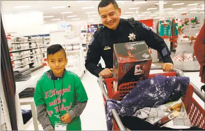  ?? GARY REYES — STAFF PHOTOGRAPH­ER ?? David Gonzales, 10, shops with Officer Ramiro Perez of the Redwood City Police Department during the annual Shop with a Cop Heroes and Helpers Shopping Spree held at the Target store in San Jose on Wednesday.