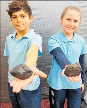  ??  ?? Sailah James (10) and Emma Steele (11) hold a meteorite, with the Starlab Dome behind them.