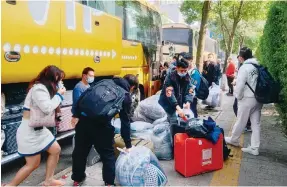  ?? Photo: The Paper ?? Passengers prepare to take a bus to Foxoconn’s Zhengzhou plant earlier this month.