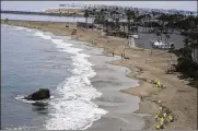  ?? RINGO H.W. CHIU / AP ?? Workers in protective suits clean the contaminat­ed beach in Corona Del Mar after an oil spill in Newport Beach, Calif. California’s uneasy relationsh­ip with the oil industry is being tested again by the latest spill.