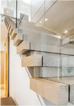  ??  ?? Left: The custom staircase adds panache to the entry, with skylights drawing in plenty of natural light, and solar-powered automated blinds. The treads seem to pass right through the glass. The wall is lined in wood panels up the stairs, and above the landing is a wall of horizontal tile the colour of driftwood.