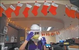  ?? Jae C. Hong The Associated Press ?? Nurse Romina Pacheco disinfects her powered air-purifying respirator Monday after tending to a patient in a COVID-19 unit decorated with Christmas stockings with nurses’ names written on them at Mission Hospital in Mission Viejo, Calif.