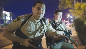  ?? "1 1)050 ?? Police officers advise people to take cover near the scene of a shooting near the Mandalay Bay resort and casino on the Las Vegas Strip.