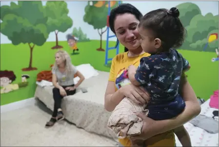  ?? PHOTOS BY MARTA LAVANDIER — THE ASSOCIATED PRESS ?? Isabel Bembow Tamayo holds Liam Centeno, 1, in the Iglesia Rescate school classroom that is converted into a bedroom for her family on Feb. 21in Hialeah, Fla. Isabel, her mother and two siblings arrived on an overcrowde­d boat from Cuba.