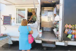  ?? SETH BIRKENMEYE­R/STAFF FILE ?? Channing Richardson orders from Dana Planks outside Virginia Beer Co. in this file photo. Many food trucks can’t operate amid the pandemic.