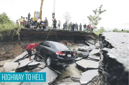  ?? Picture: EPA-EFE ?? Thai officers hoist a damaged car out of a collapsed road after a portion of a highway caved in following heavy floods in the Thepha district in Songkhla province, southern Thailand, yesterday.