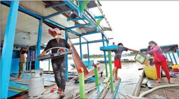  ?? HONG MENEA ?? Floating home owners remove their belongings along the rivers in Prek Pnov commune in Phnom Penh’s Prek Pnov district on Sunday.