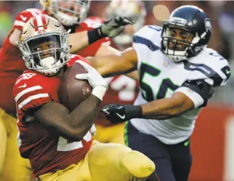  ?? John Hefti / Associated Press ?? 49ers running back Carlos Hyde carries the ball against the Seahawks during the second half. He gained 47 yards on the ground and caught seven passes Sunday afternoon in Santa Clara.