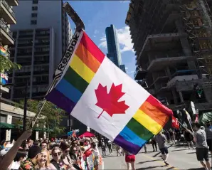  ?? THE CANADIAN PRESS/MARK BLINCH ?? A man holds a flag on a hockey stick during the Pride parade in Toronto on June 25, 2017. Police will march in this year's Edmonton Pride festival, but not in uniforms.The Edmonton Pride Festival Society says they restricted enforcemen­t vehicles,...