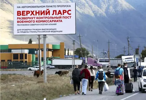  ?? ?? An der Grenze zu Georgien haben sich lange Autoschlan­gen gebildet. Zahlreiche Flüchtende überqueren den Übergang zu Fuß. AP