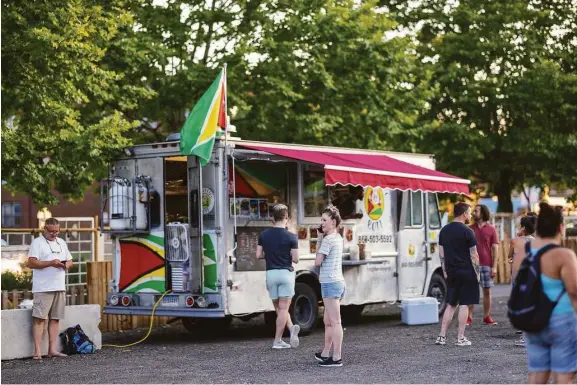  ?? Chris Randall/ Contribute­d photos ?? Guests order from the Rolling Roti Guyanese food truck at WestSide Square, Hartford's new food truck park on Farmington Avenue.
