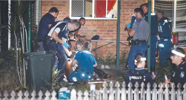  ??  ?? AFTERMATH: A man is treated for stab wounds in the front yard of a house at Earlville on Thursday night. Picture: ANNA ROGERS