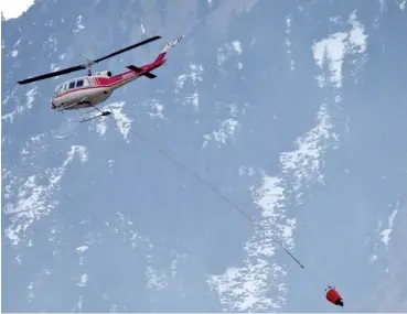  ?? AP PHOTO/DAVID ZALUBOWSKI ?? Framed against the Flatirons, a helicopter makes a drop on a wildfire burning near the National Center for Atmospheri­c Research on Sunday in Boulder, Colo.