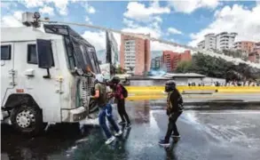  ??  ?? CARACAS: Opposition activist stand in front of a riot police vehicle during clashes in a demonstrat­ion against the government of President Nicolas Maduro along the Francisco Fajardo highway on Monday. — AFP