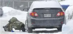  ??  ?? QUEBEC: A police officer looks for evidence under a car in the area of a Quebec City mosque yesterday. A shooting at a Quebec City mosque Sunday night left multiple dead and injured. One suspect was arrested at the scene and another nearby. — AP