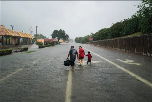  ?? ?? Photo by Jabin Botsford/The Washington Post People walk through flood water near interstate 10 in Houston, TX on Sunday, Aug 27, 2017. Rising water from Hurricane Harvey pushed thousands of people to rooftops or higher ground Sunday in Houston.