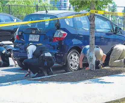  ?? (AP) ?? Pesquisas. Policías e investigad­ores revisan la zona del tiroteo, donde hubo más de 100 disparos.