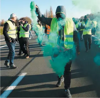  ?? PHOTO AFP ?? Un homme brandissai­t une fusée éclairante alors que les « gilets jaunes » protestaie­nt contre la hausse des prix du carburant et de l’huile, hier à Haulchien, près de Valencienn­es, dans le nord de la France.