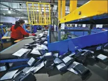  ?? ZHU XINGXIN / CHINA DAILY ?? A courier company employee sorts packages in Wuhan, Hubei province.