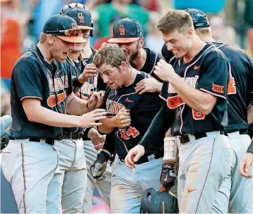  ?? [PHOTO BY NATE BILLINGS, THE OKLAHOMAN] ?? Colin Simpson, center, is greeted by teammates after hitting one of his two homers on Thursday against West Virginia at Chickasaw Bricktown Ballpark. The Cowboys beat the Mountainee­rs, 8-4.