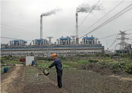  ?? GETTY IMAGES ?? A Chinese man waters his vegetable patch next to a coal-fired power plant in Hanchuan, Hubei province. China will no longer help to build such projects in other countries – raising the difficult question of how to get those countries to adopt renewable energy sources to fuel their developmen­t.