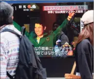  ?? Koji Sasahara / Associated Press ?? People walk past a television screen showing golfer Hideki Matsuyama on a news channel in Tokyo. From Japan’s prime minister on down, the country celebrated Matsuyama’s victory in the Masters.
